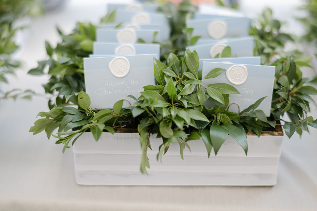 Escort cards featuring custom white wax seal; folded soft blue paper and custom calligraphy on vellum